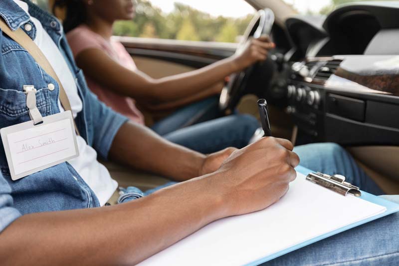 driving-instructor-writing-down-results-of-exam-d-2021-12-09-07-40-20-utc